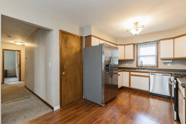 a kitchen with granite countertop stainless steel appliances a refrigerator cabinets and wooden floor