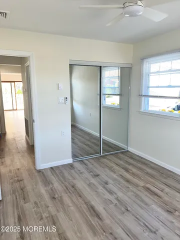 an empty room with wooden floor mirror and windows