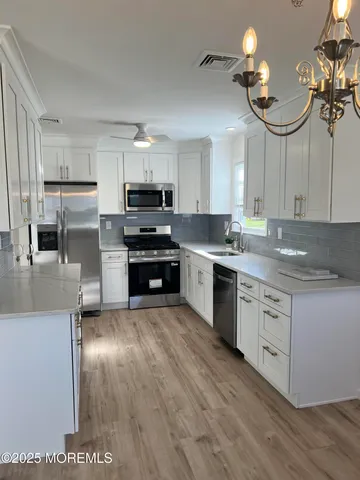 a kitchen with kitchen island granite countertop a sink cabinets and stainless steel appliances