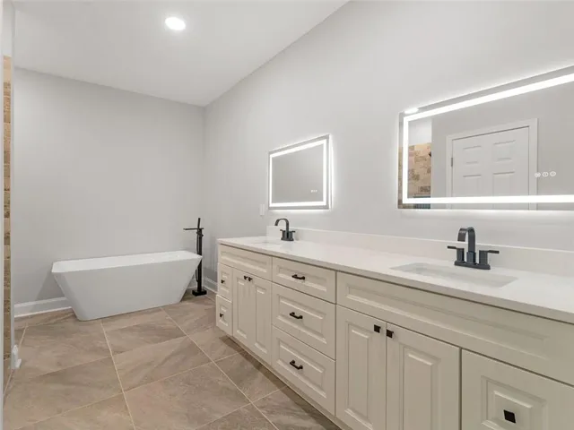 a spacious bathroom with double sink a bathtub and a window