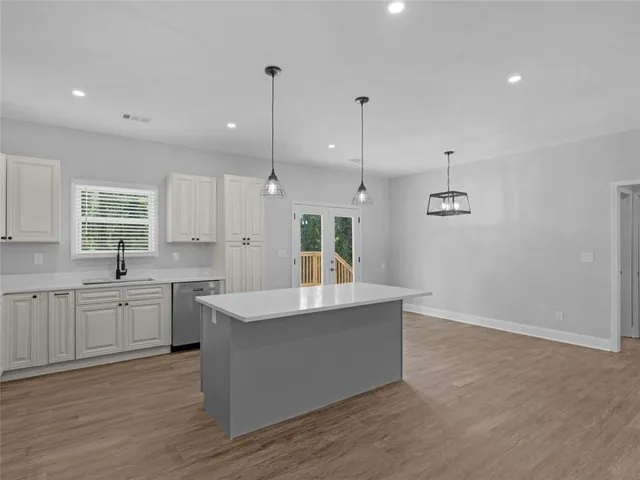 a large kitchen with stainless steel appliances a large counter top a sink a refrigerator and a window