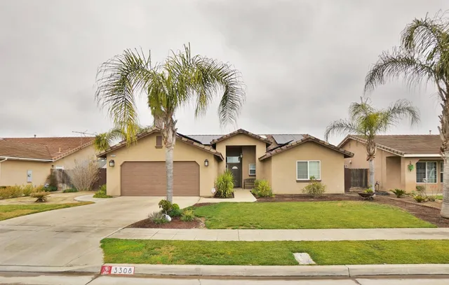 a front view of a house with a garden and palm trees