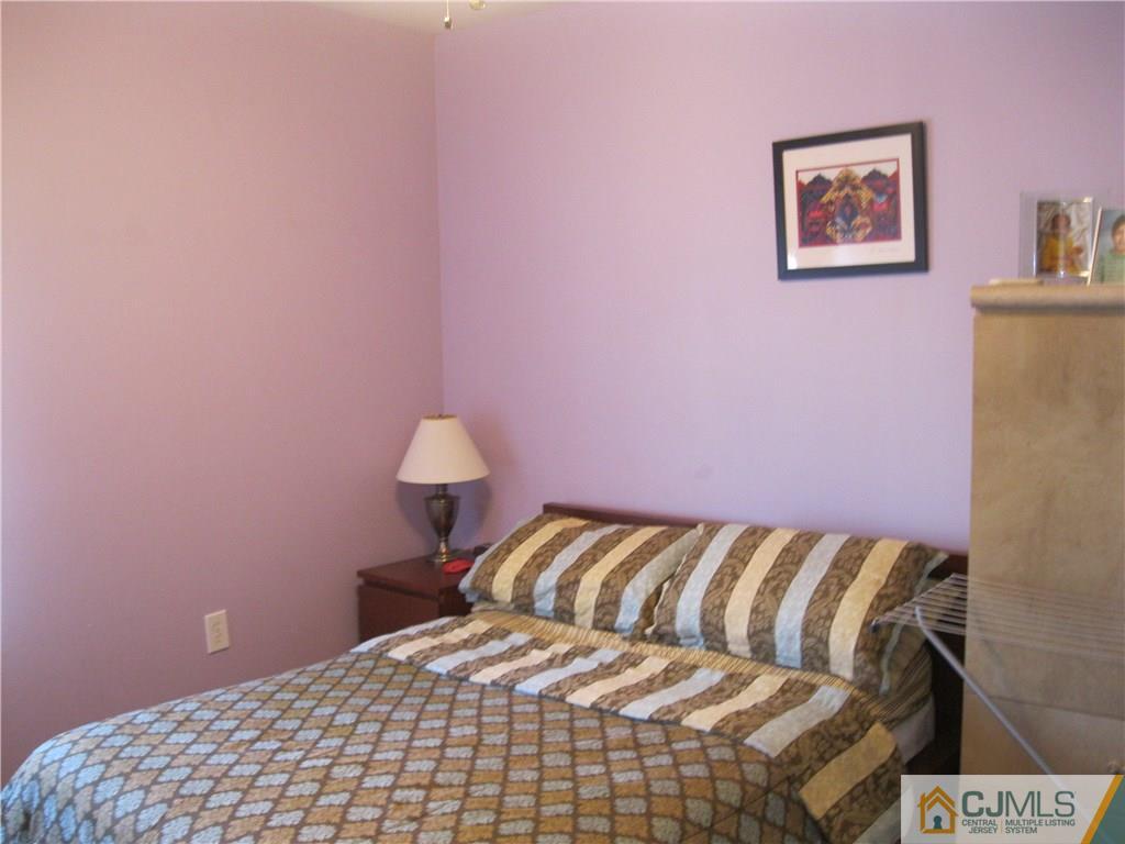 2201 Timber Ridge Court Sayreville, NJ 08859 - Photo 13 of 17 a bedroom with a bed and a lamp on the dresser