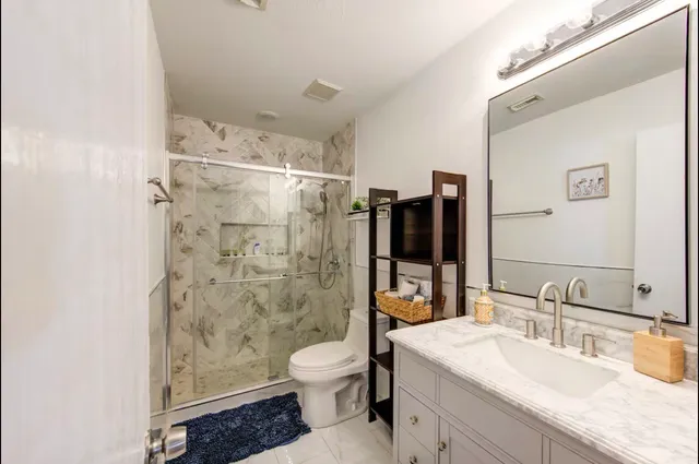 a bathroom with a granite countertop sink a toilet and a mirror