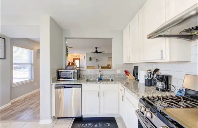 a kitchen with granite countertop white cabinets and stainless steel appliances