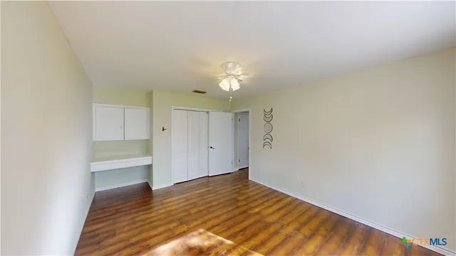 a view of a room with wooden floor and a ceiling fan