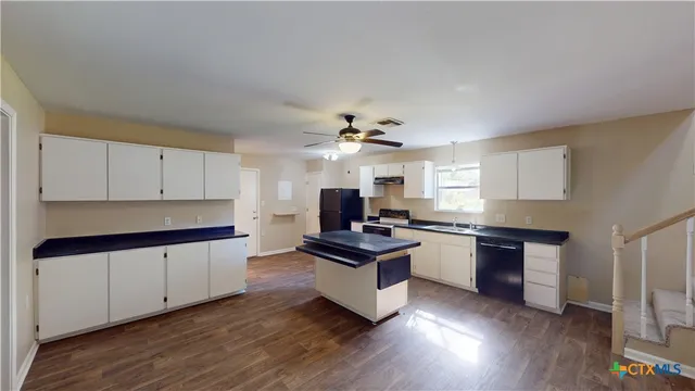 a kitchen with granite countertop a stove top oven and cabinets