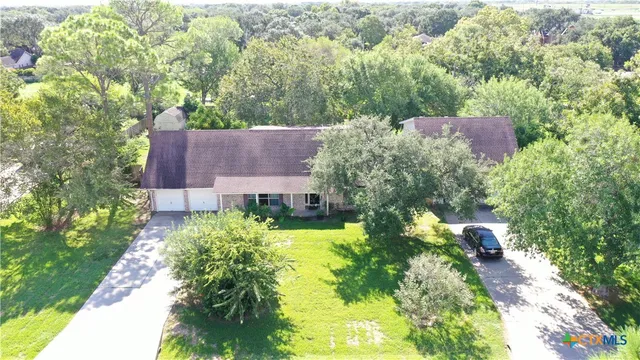an aerial view of a house with a yard and large trees