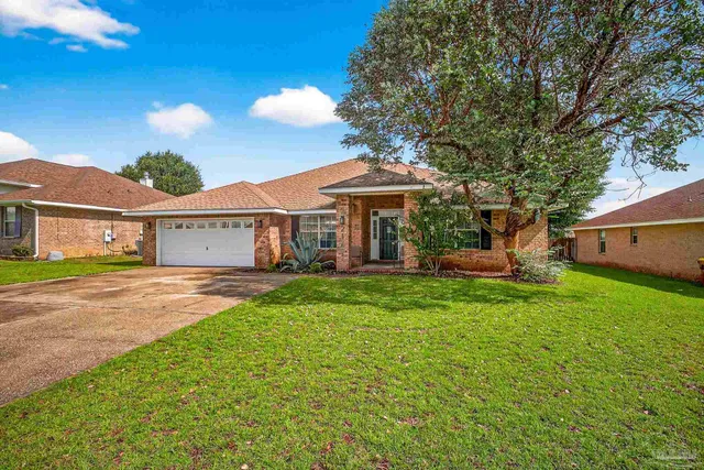 a view of a house with backyard and a tree