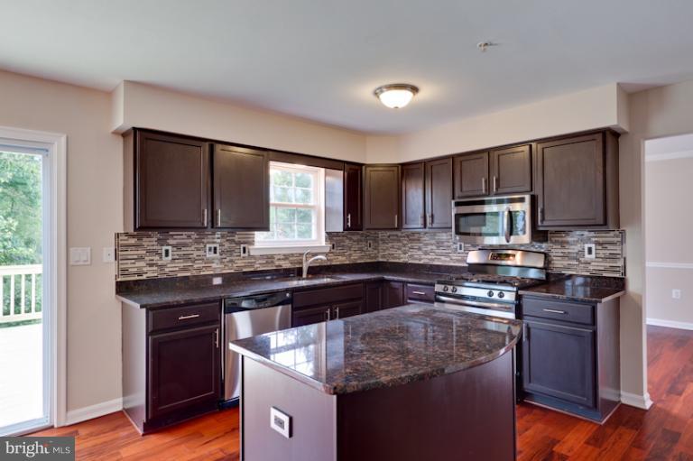 5919 Plata Street Clinton, MD 20735 - Photo 4 of 25 a kitchen with kitchen island granite countertop a sink stove and refrigerator