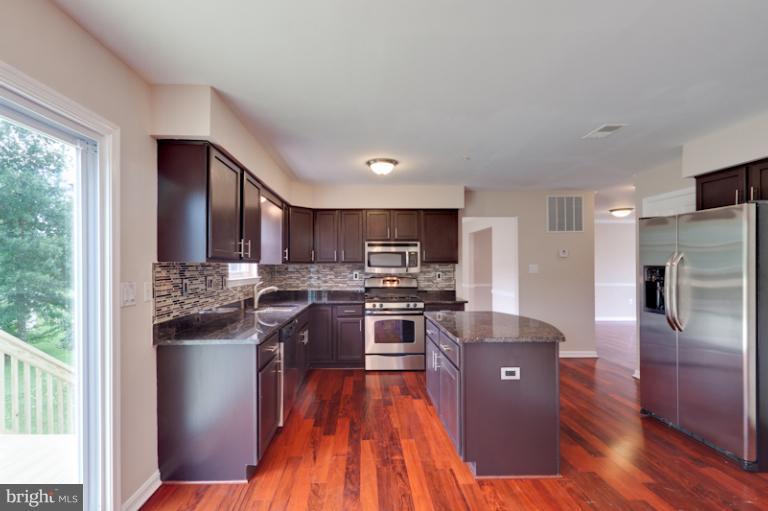 5919 Plata Street Clinton, MD 20735 - Photo 5 of 25 a kitchen with stainless steel appliances granite countertop a stove top oven a sink and a refrigerator
