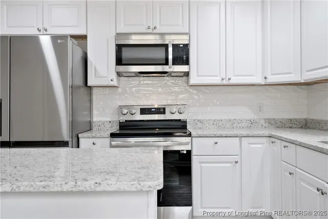 a kitchen with stainless steel appliances granite countertop a stove a microwave and a refrigerator