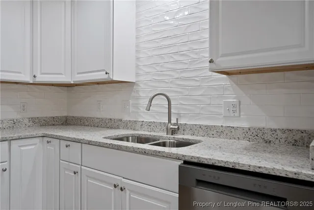 a sink with granite countertop white cabinets and a sink