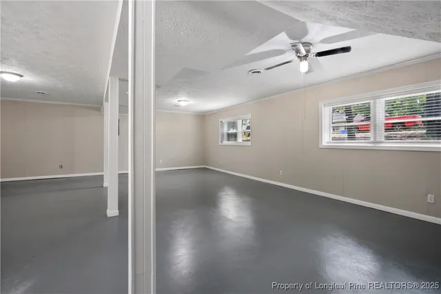 an empty room with wooden floor fan and windows