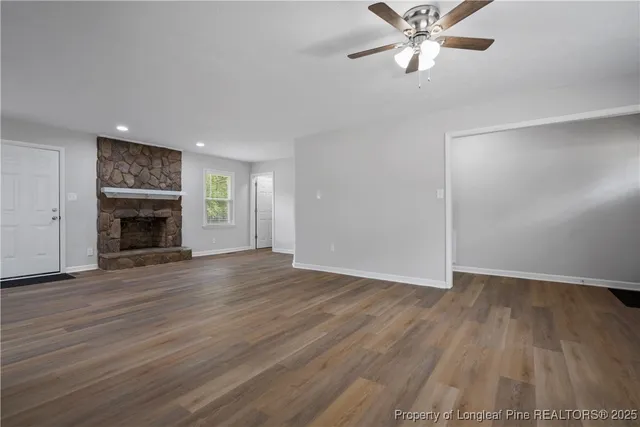 an empty room with wooden floor fireplace and windows