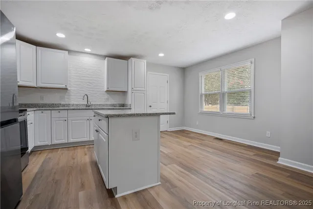 a kitchen with stainless steel appliances granite countertop a stove a sink dishwasher and a refrigerator with wooden floor