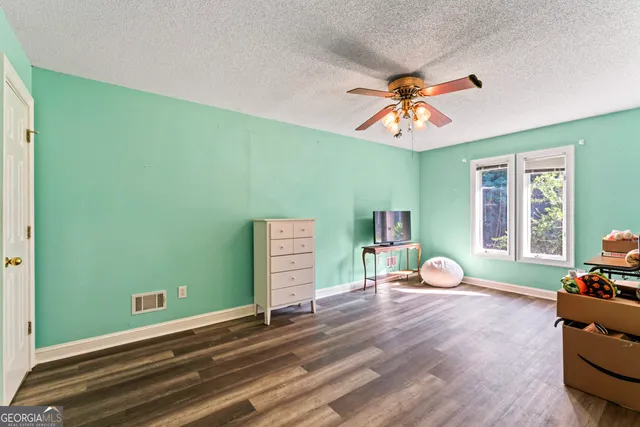 a view of a livingroom with wooden floor and a ceiling fan