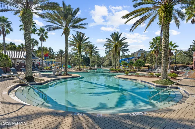 a view of a swimming pool with a patio and palm trees
