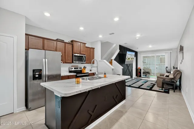 a large kitchen with stainless steel appliances a large counter top a sink refrigerator and cabinets