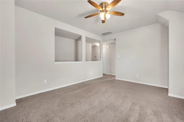 an empty room with a chandelier fan and windows
