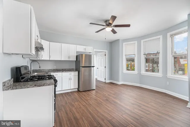 a kitchen with a refrigerator a stove cabinets and wooden floor