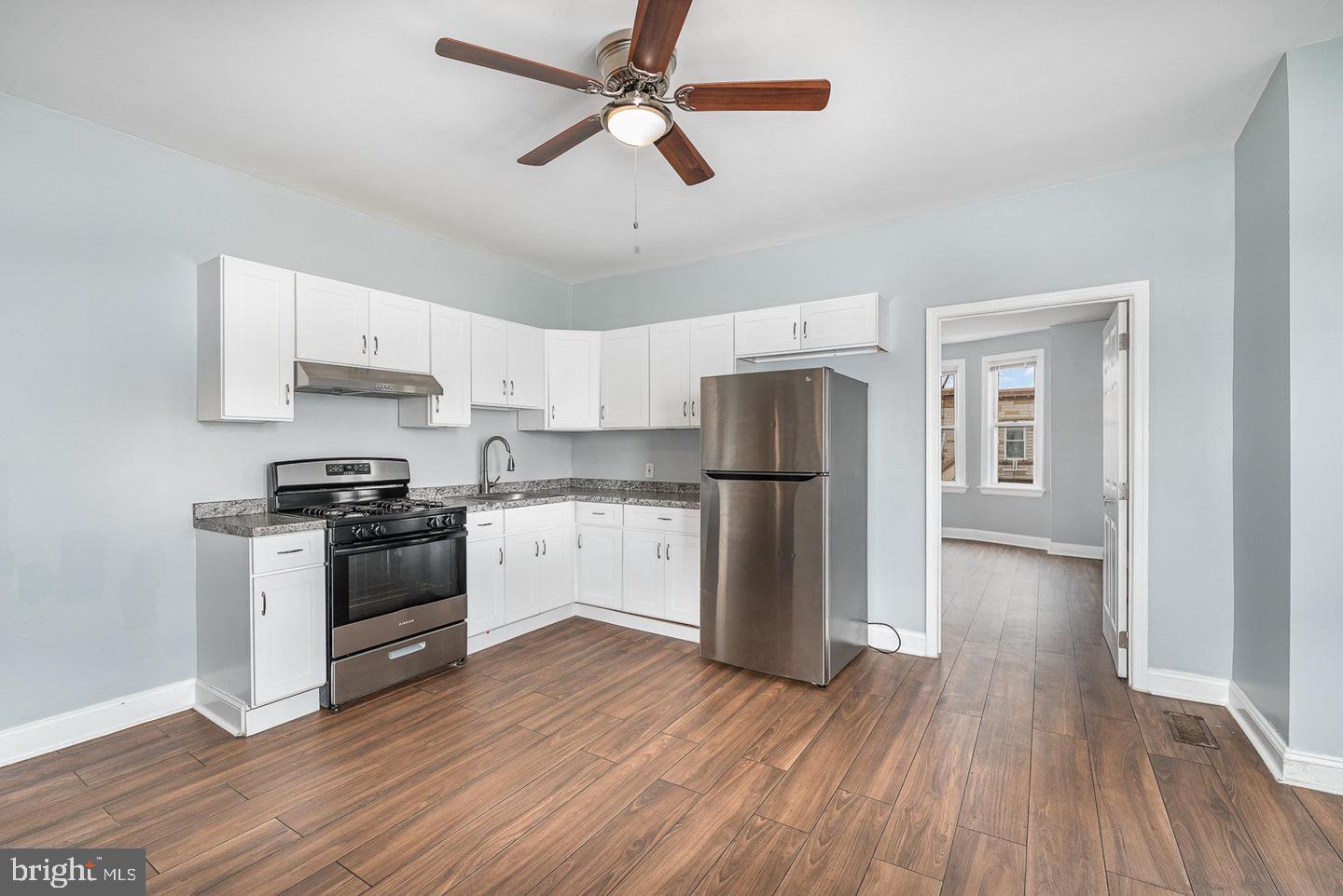 4600 Eastern Avenue Baltimore, MD 21224 - Photo 8 of 25 a kitchen with stainless steel appliances a refrigerator a stove a sink and white cabinets with wooden floor