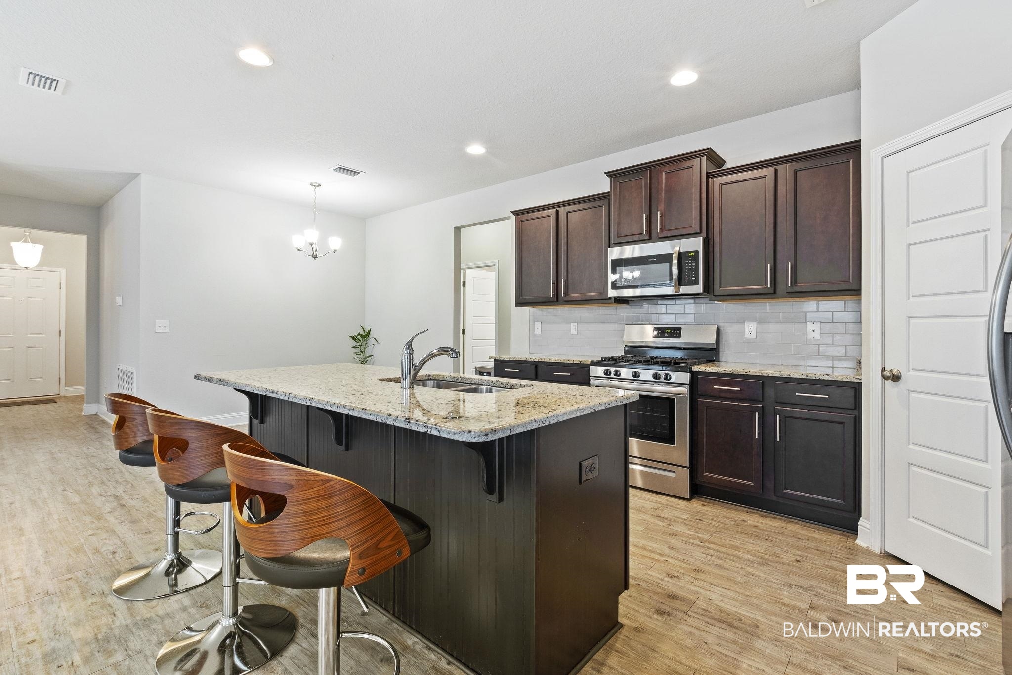 31643 Kestrel Loop Daphne, AL 36527 - Photo 11 of 59 Kitchen with light wood-type flooring, light stone countertops, stainless steel appliances, sink, and a kitchen island with sink