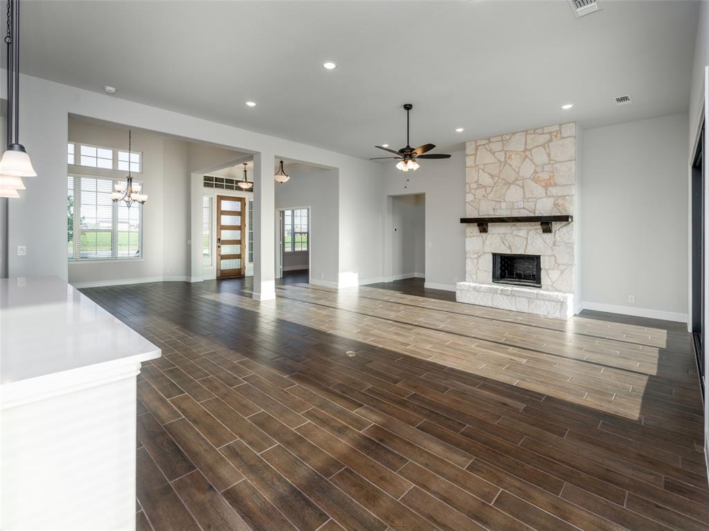 2108 Charters Circle Nevada, TX 75173 - Photo 14 of 37 Unfurnished living room featuring a ceiling fan, recessed lighting, dark wood-style floors, a stone fireplace, and a chandelier