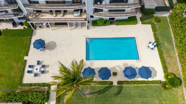 a view of swimming pool with lawn chairs and plants