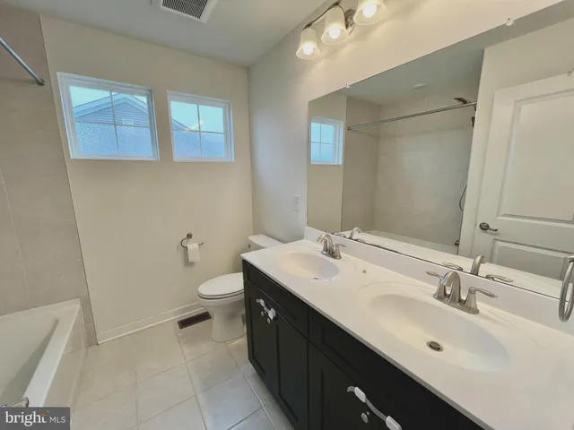 a bathroom with a double vanity sink a toilet and a mirror