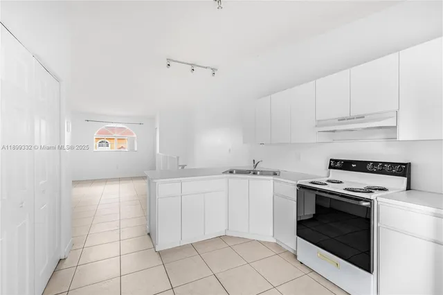 a kitchen with granite countertop a stove top oven and cabinets