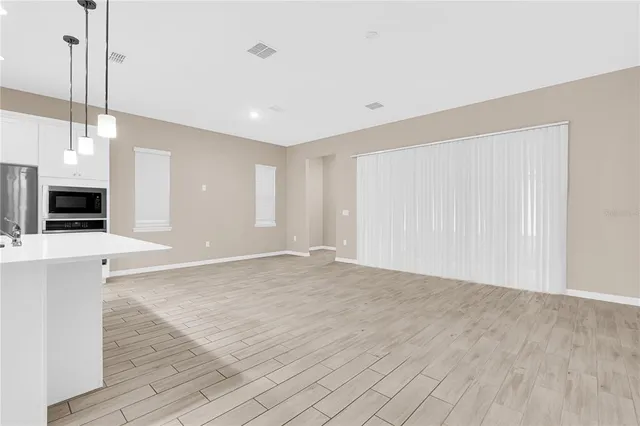 a view of an empty room with fireplace and wooden floor