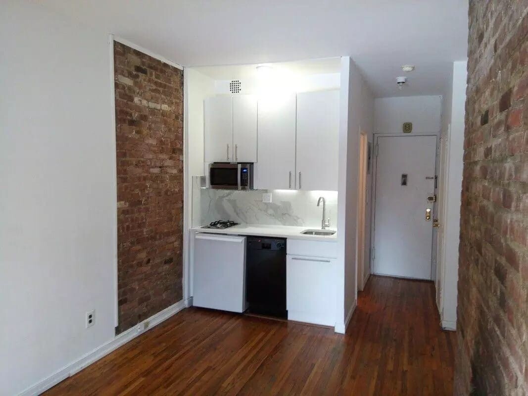 210 East 21st Street, Unit 6B Manhattan, NY 10010 - Photo 4 of 6 a kitchen with kitchen island wooden floors and stainless steel appliances