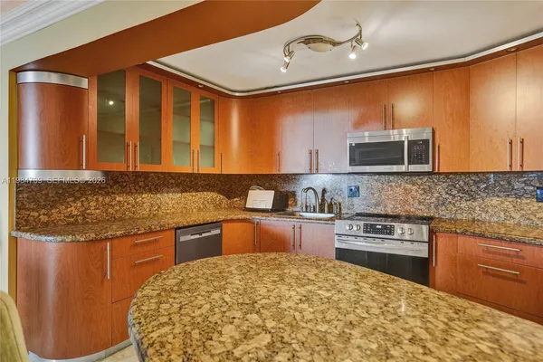 a kitchen with stainless steel appliances granite countertop a sink and a refrigerator