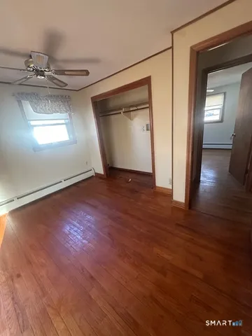 an empty room with wooden floor cabinet and windows