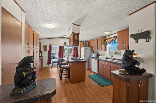 a kitchen with stainless steel appliances kitchen island granite countertop a sink dishwasher a stove and a refrigerator with wooden floor