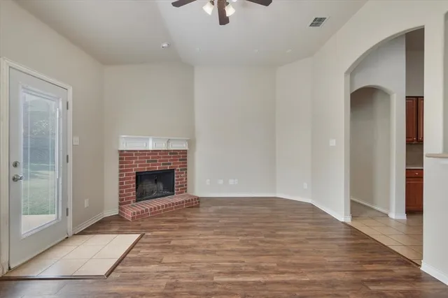 a view of an empty room with wooden floor fireplace and a window