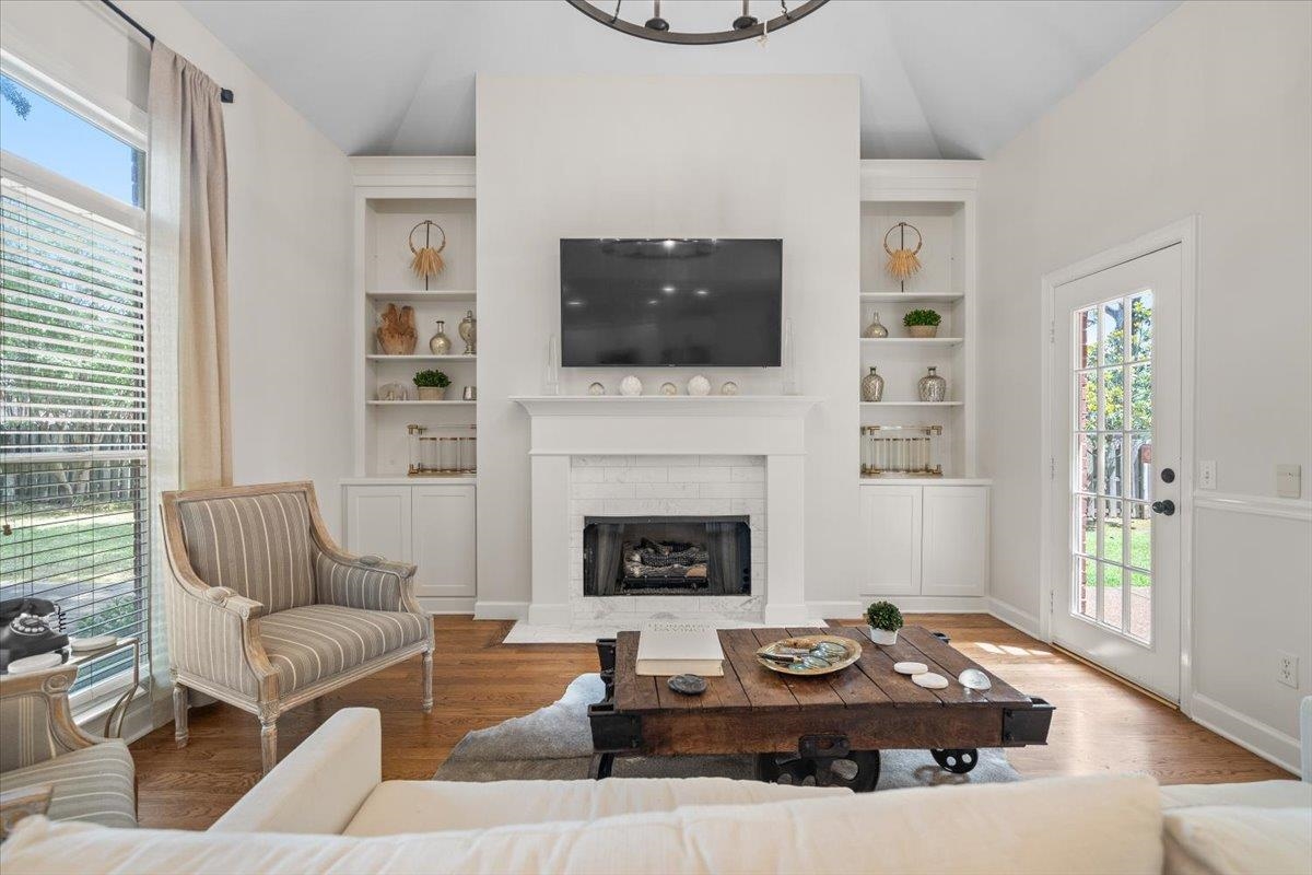 1876 Liles Lane Collierville, TN 38017 - Photo 8 of 36 Living area featuring a fireplace with a white mantel, built-in shelving, wood-finish flooring, and a glass-paned exterior door