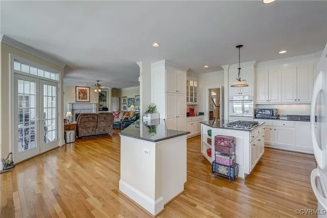 a large kitchen with stainless steel appliances granite countertop a stove top oven a sink dishwasher and a dining table with wooden floor