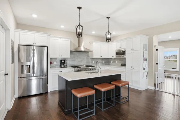 a kitchen with stainless steel appliances granite countertop a refrigerator a stove a sink dishwasher and a stove with wooden floor