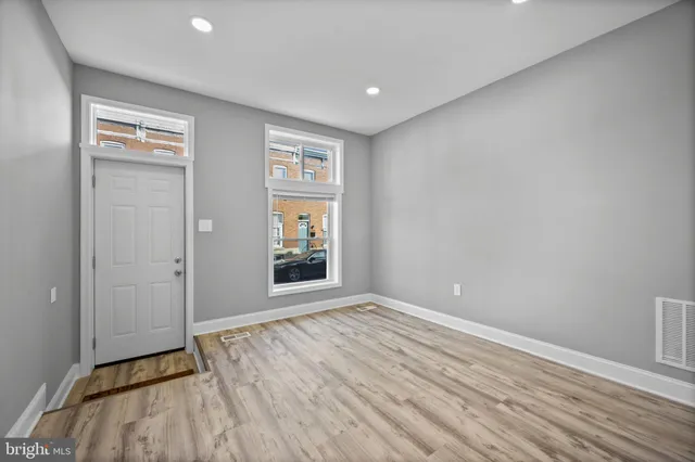 a view of a big room with wooden floor and windows