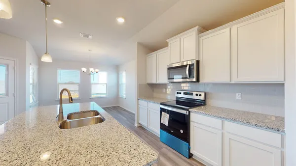 a kitchen with granite countertop a sink a stove and cabinets