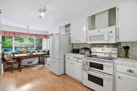 a kitchen with white cabinets and appliances