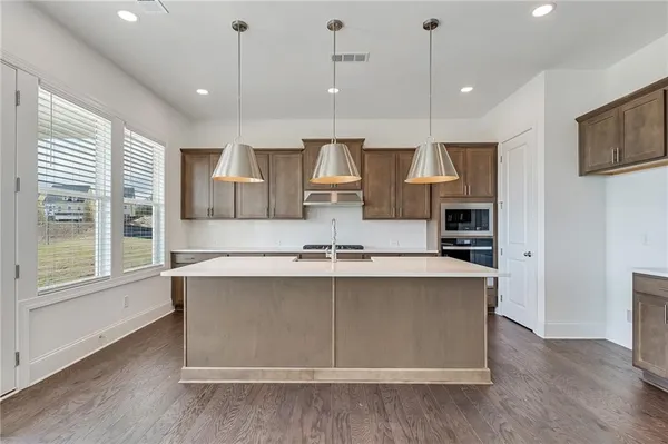 a large kitchen with stainless steel appliances a large counter top a sink a refrigerator and a window