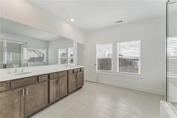 a large bathroom with a double vanity sink a large mirror and a bathtub