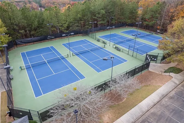 a view of a tennis ground with large trees