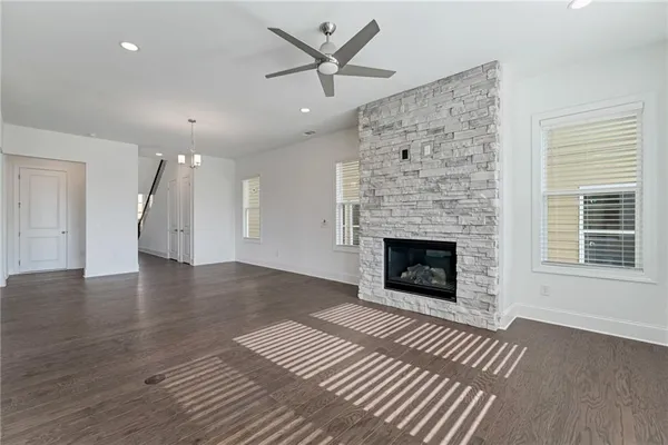 an empty room with a fireplace wooden floor and a ceiling fan