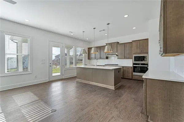 a large kitchen with stainless steel appliances a large counter top a stove a sink and a refrigerator