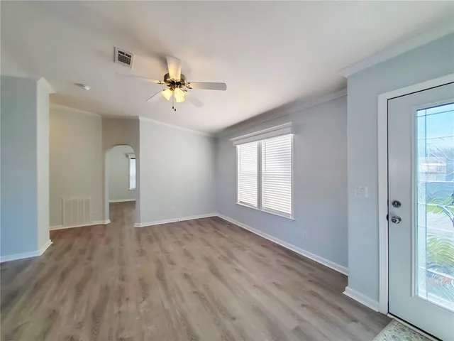 a view of empty room with wooden floor and fan