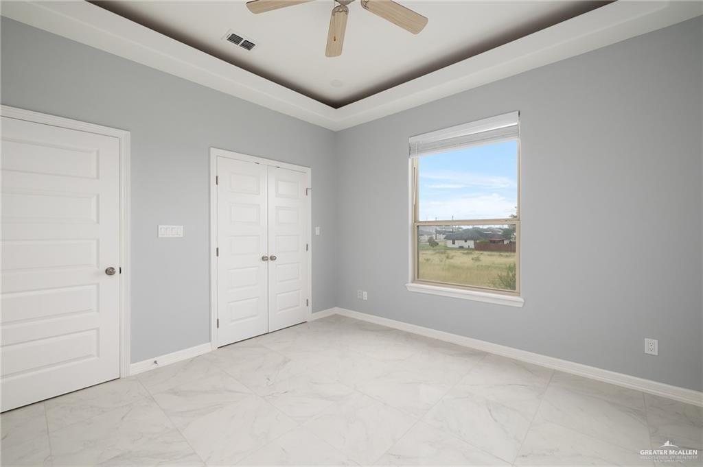5307 North Crown Point Pharr, TX 78577 - Photo 10 of 11 Unfurnished bedroom featuring light marble finish floors, ceiling fan, and a closet